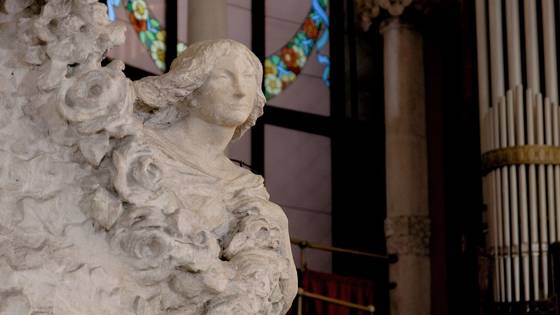 A stone bust among flowers, stained glass behind