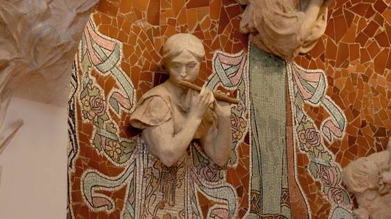 A muse playing a flute on orange broken-tile mosaic